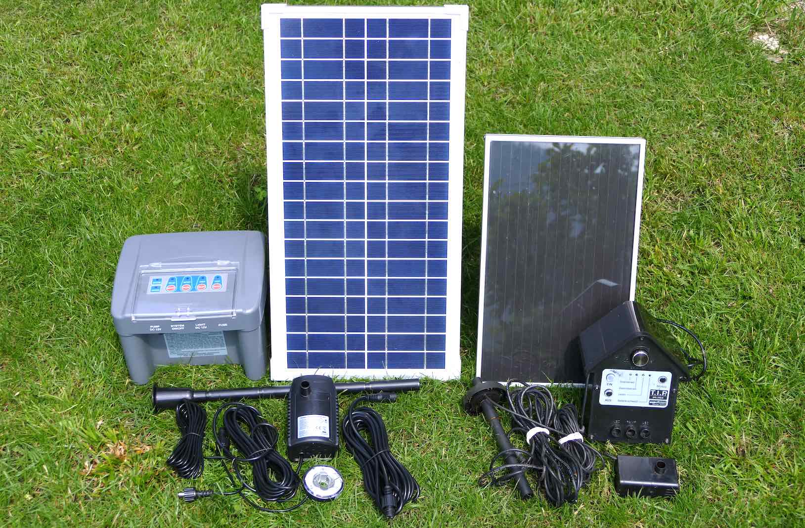 Verschiedene Solartechnik-Komponenten für den Garten auf einer Wiese, darunter Photovoltaik-Panele und Steuergeräte