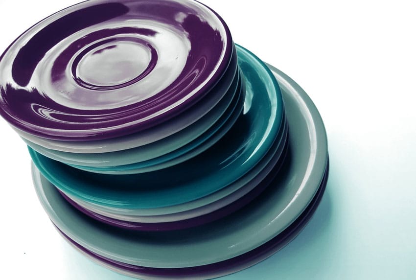 Stapel bunter Untertassen in Violett, Türkis und Grau, glänzend