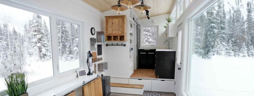 Innenausbau eines Tiny Houses mit viel Stauraum, Schiebetür und Blick auf eine verschneite Landschaft