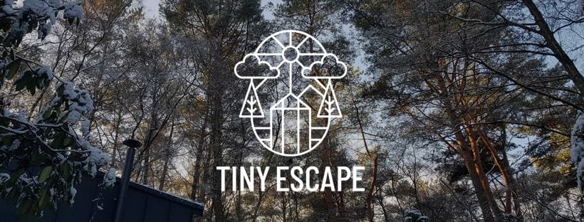 Logo von Tiny Escape vor winterlicher Waldkulisse mit schneebedeckten Bäumen und blauem Himmel