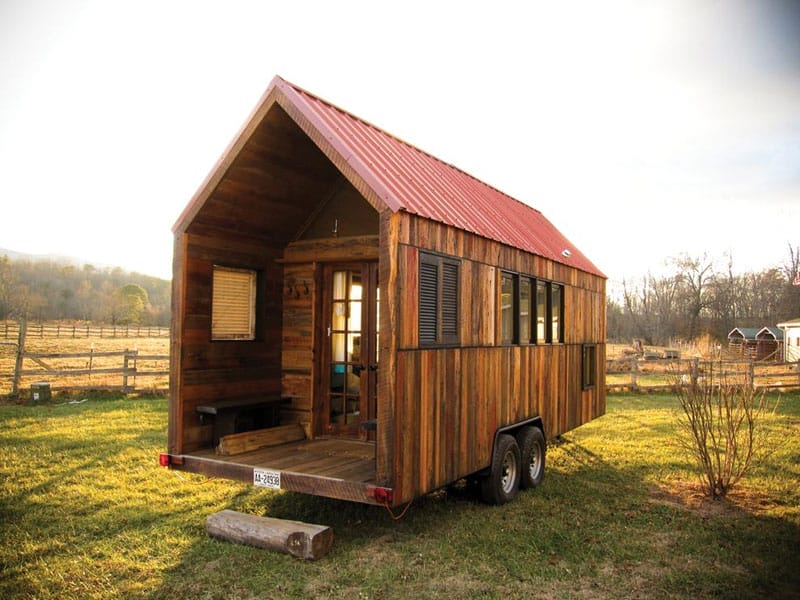 Ein Tiny House mit Satteldach und rotem Dach, steht auf einem Anhänger