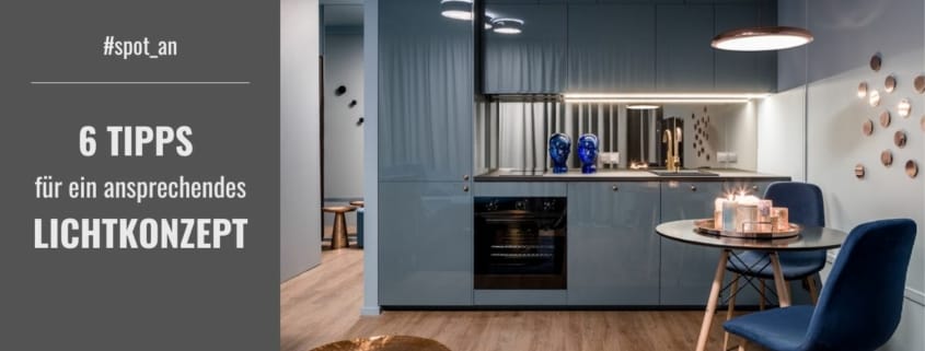 Eine moderne Küche mit blaugrauen Schränken, hellem Holzfußboden und einer kleinen Essecke mit dunklem Tisch und zwei Stühlen
