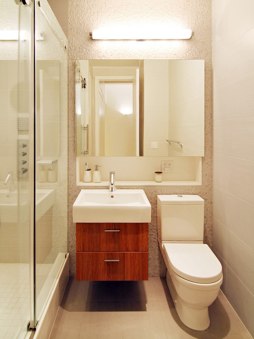 Kleines Badezimmer mit Duschkabine, Waschbecken mit Holzunterschrank, Spiegelschrank, WC und Wandlampe