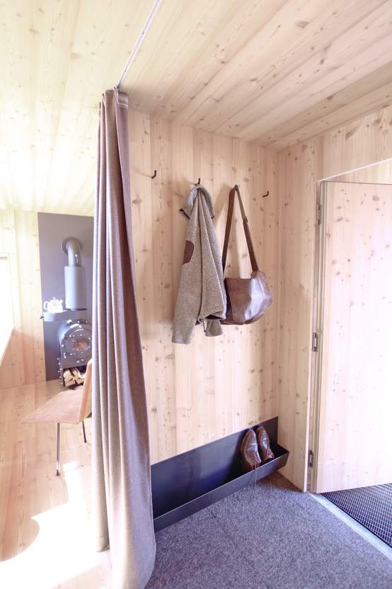 Der Eingangsbereich vom Ufogel: Garderobe mit Mantel und Tasche, Schuhablage und Ofen im Hintergrund