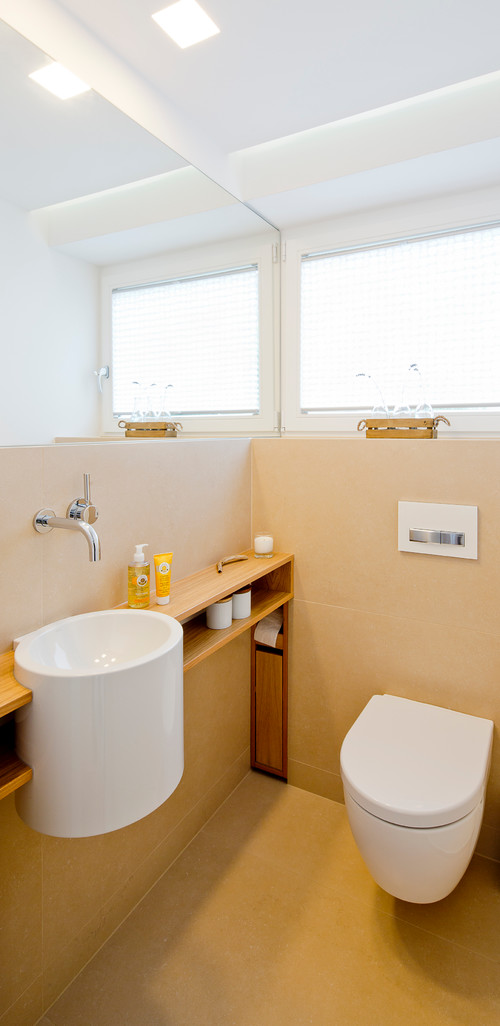 Modernes, kleines Badezimmer mit Handwaschbecken, WC, Holzablage und zwei Fenstern mit Jalousien
