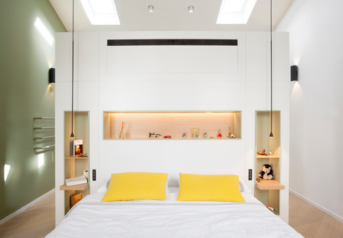 Ein helles Schlafzimmer in Weiß und Grün mit gelben Akzenten, in das durch Dachfenster Licht fällt