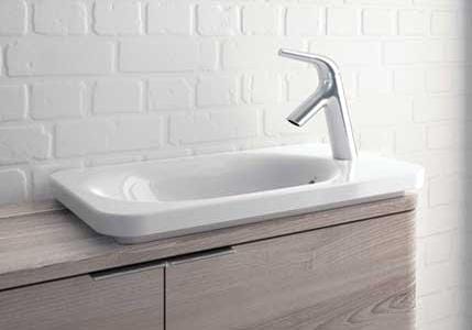 Weißes Waschbecken von VitrA mit modernen Armaturen auf einem Holzunterschrank vor einer weißen Ziegelwand