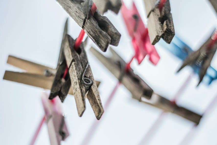 Nahaufnahme von Wäscheklammern aus Holz und farbigem Plastik, die auf einer roten Wäscheleine stecken