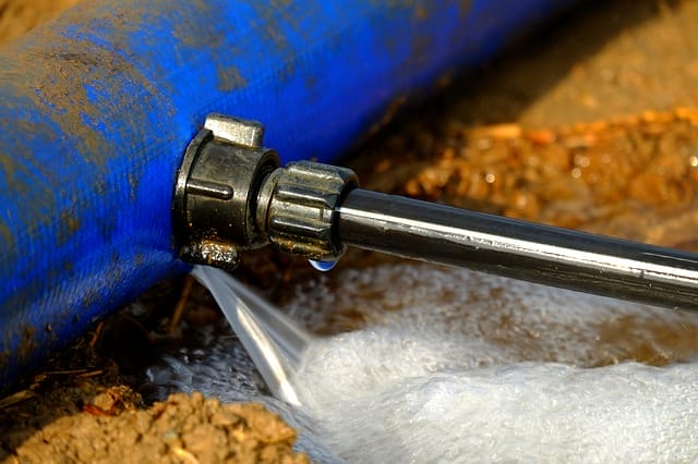 Verbindung von blauem Rohr und Metallschlauch mit undichter Stelle,ichter Stelle, aus der Wasser spritzt