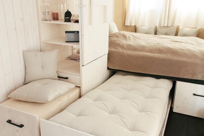 Innenansicht Wohnwagon mit Bett, Ausziehbett, Regalsystem und Bose SoundLink Bluetooth-Lautsprecher von Bose