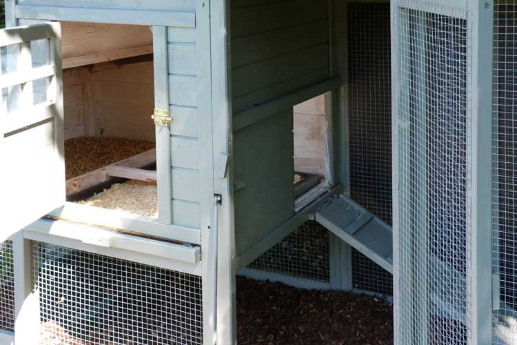 Detailaufnahme eines günstigen Hühnerstalls mit geöffneter Seitenklappe und Einstreu