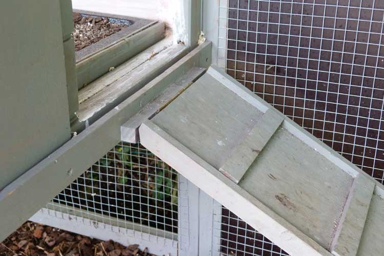 Nahaufnahme einer Hühnerstall-Rampe aus Holz und Gitterelementen des Auslaufiguriert, mit Klebeband und Dreckspuren