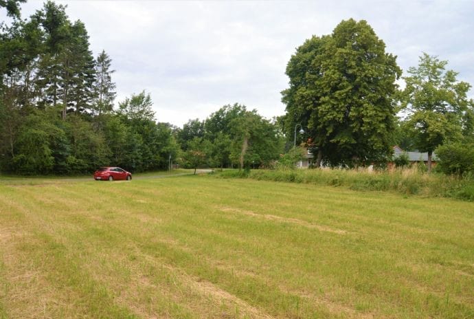 Pachtgrundstück in Neu-Darchau unter bewölktem Himmel, rote Limousine fährt in Seitenstraße