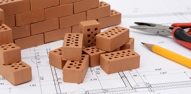 Ziegelsteine auf einem Bauplan mit Bleistift und Zange