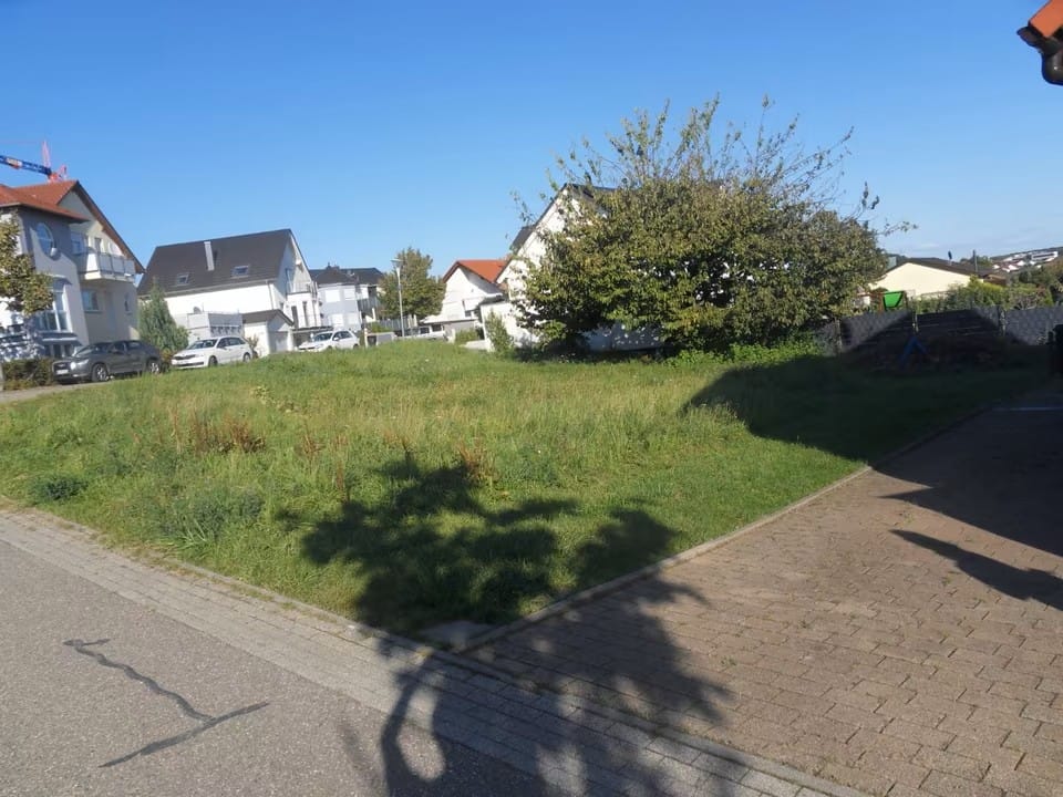 Unbebautes, vollständig erschlossenes Grundstück in Kirchardt, umgeben von Wohnhäusern und Bäumen, bei Sonnenschein