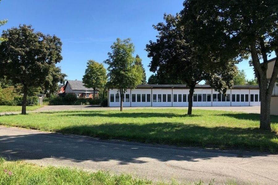 Grundstück eines ehemaligen Bauhofs in Coburg mit Wiese, asphaltierter Fläche und einem langen weißen Gebäude