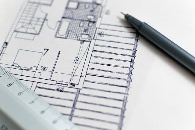 Architektenplan mit Grundriss, darauf liegen ein Geodreieck und ein Stift