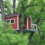 Rotes Baumhaus des Hotell Hackspett in einem belaubten Baum