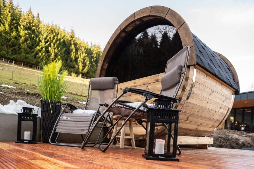 Terrasse aus Holzbohlen mit zwei braunen Liegestühlen und einem sichtbaren Teil des Minihauses "Klitzeklein"