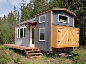 Ana White Tiny House „Rustic Modern Tiny House“ auf einem Trailer stehend, mit Holzterrasse