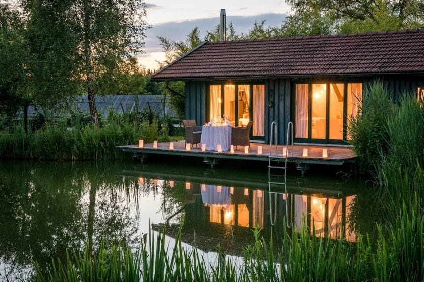 Seeterrasse am Hofgut Hafnerleiten mit Esstisch und Kerzenbeleuchtung vor einem beleuchteten Haus bei Dämmerung