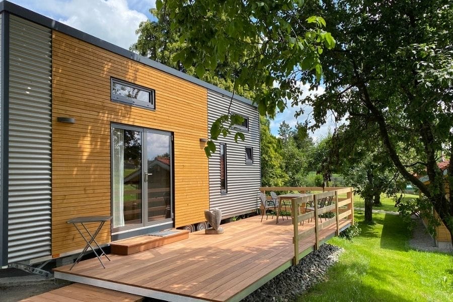 Modernes Tiny House des Ferienhofs Rummel mit Holz- und Wellblechfassade und großer Holzterrasse im Grünen