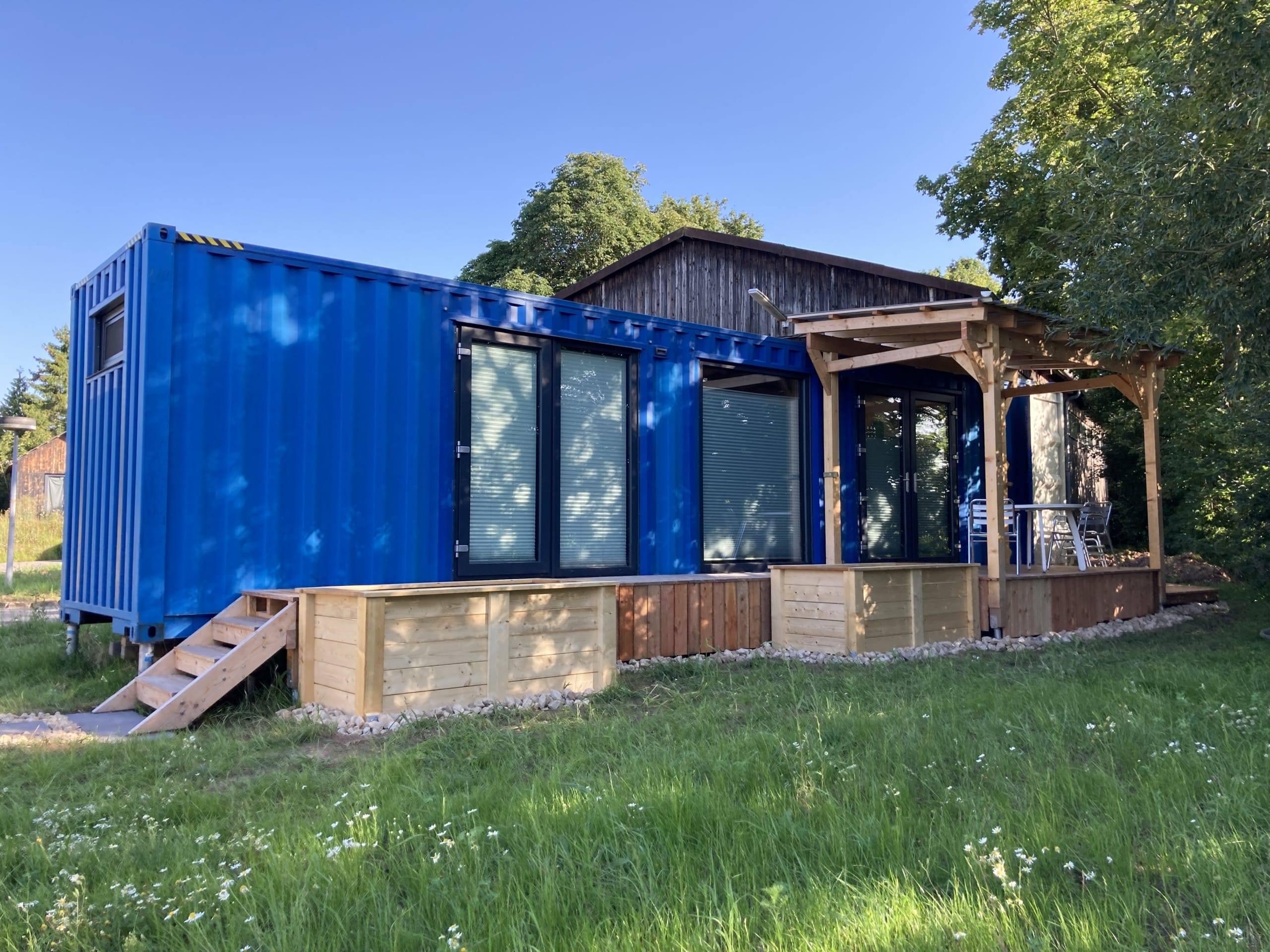 Die Steelcave, ein blaues Modulhaus auf 23 qm nahe Coburg, mit Holzterrasse und Sitzgelegenheiten