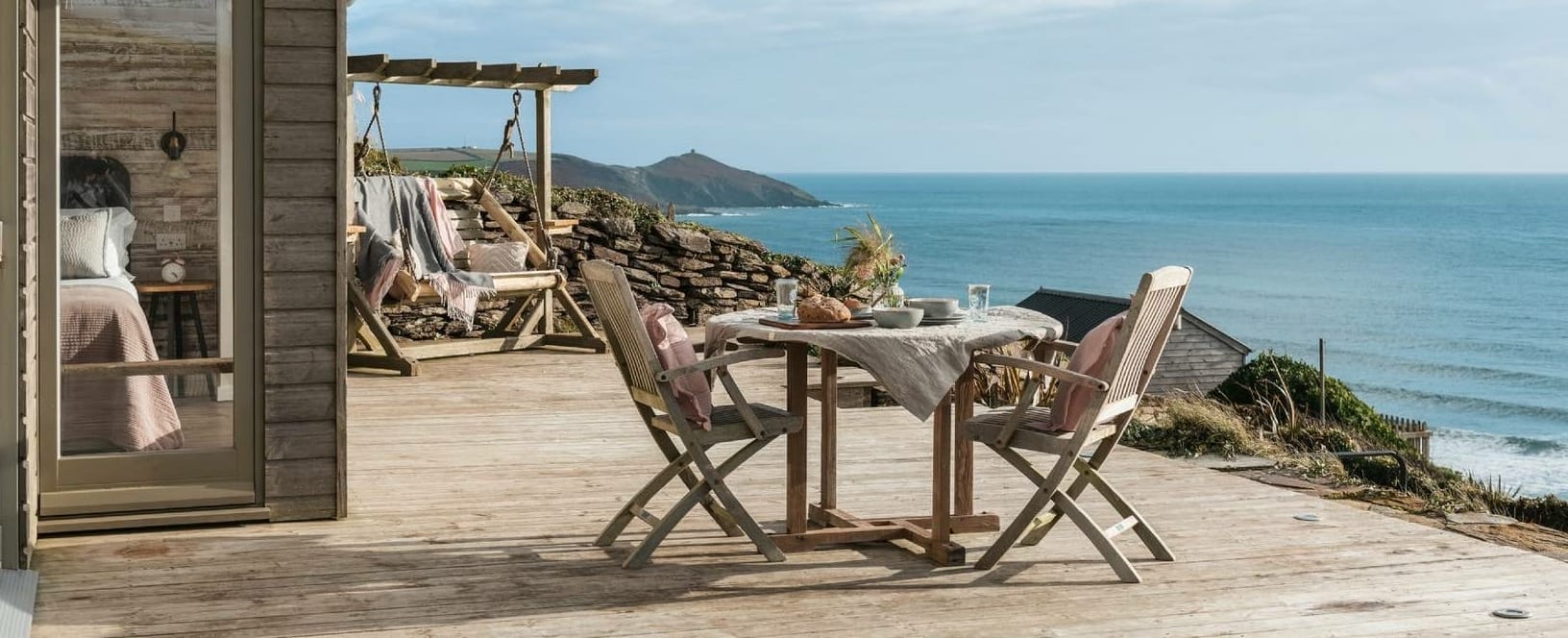 Holzterrasse vor dem Tiny House SEAGLASS mit Tisch und Stühlen, Blick auf das Meer in Cornwall (Foto: SEAGLASS, Tregonhawke,