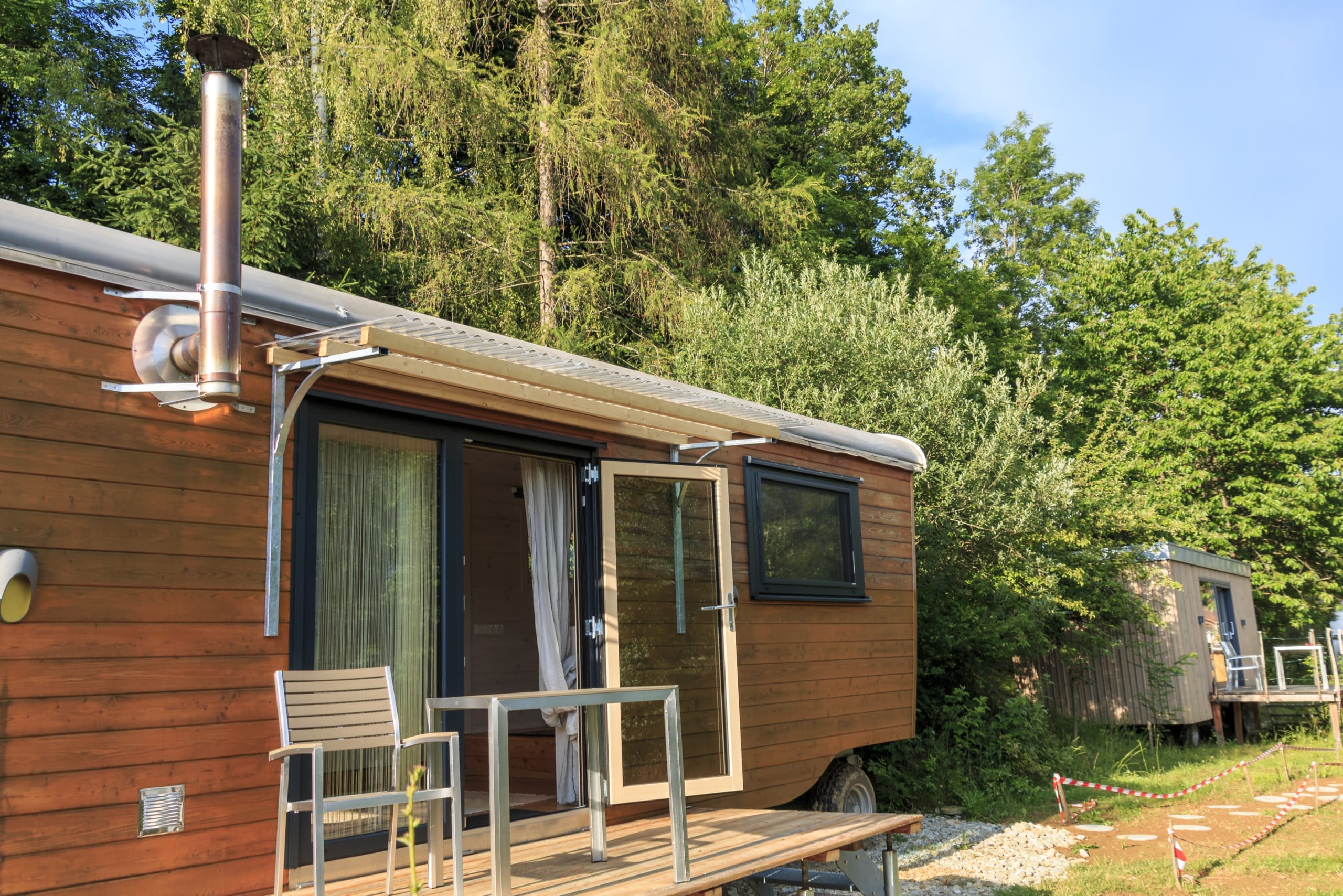 Modernes Tiny House „Steirerbua“ mit Terrasse, Tisch und Stühlen in der Natur der Oststeiermark