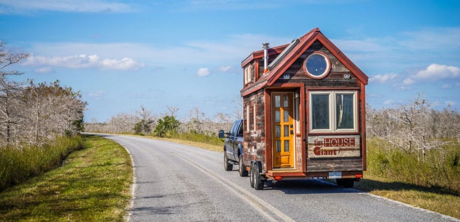 Ein Tiny House von Tiny House Giant Journey wird von einem Pick-up-Truck auf einer Landstraße gezogen