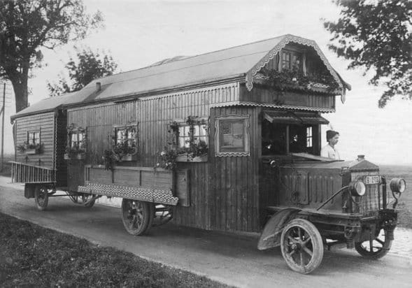 Historisches Wohnmobil mit Holzverkleidung, Verzierungen und Blumenkästen, eine Person am Steuer (offenen) Steuer (1922)