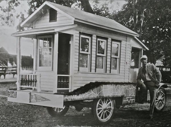 Mann lehnt an einem historischen Wohnmobil mit Haus-Aufbau aus den 1920er Jahren in den USA